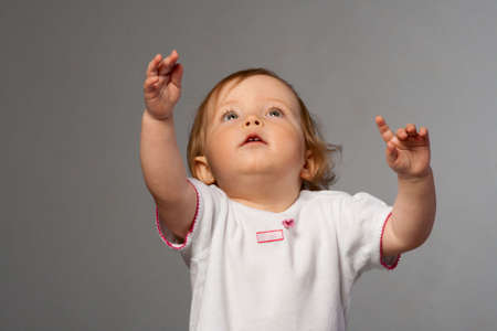 Small beauty girl reachs out her's hands for photographer.