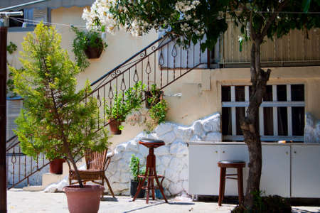 Traditional greek house. White wall, stairs, plants in tubs, window and stool.の写真素材