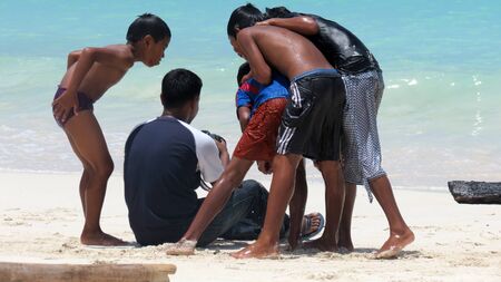 Children standing around a photographer and having a look at their photos, Andaman and Nicobar Islands, India, Asia.のeditorial素材