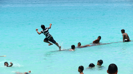 Action image of children playing on a floating log in sea, Andaman and Nicobar Islands, India, Asia.のeditorial素材