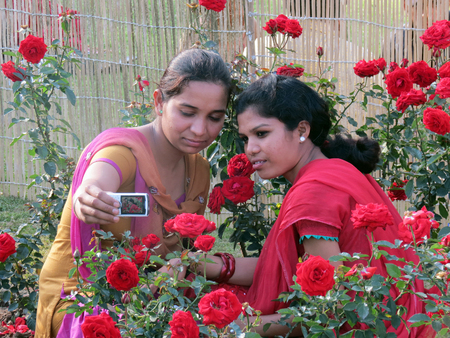 Girls taking selfie with rose flowers during rose festival in Zakir Hussain Rose Garden, Sector 16, Chandigarh, India.のeditorial素材