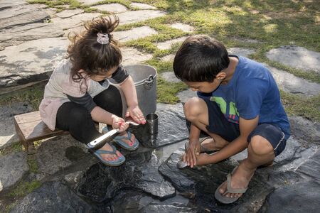 Children cleaning utensils outdoors in Shimla, Himachal Pradesh, India.の写真素材