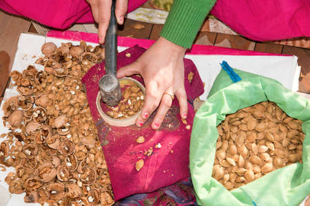 Elevated close-up view of a young woman cracking walnuts at home with a hammer.の写真素材