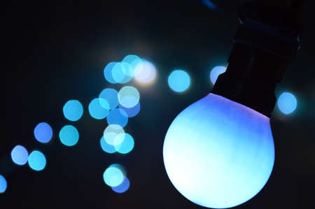 Hanging blue retro light bulb bokeh at night.の写真素材