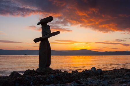 Stack of stones on the beach at sunset skylineの写真素材