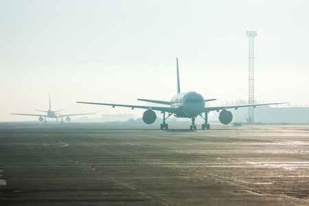 Airplanes in the fog on the airport apronの写真素材