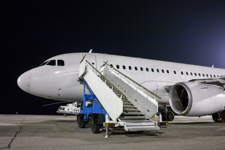 Airplane and passenger boarding steps vehicle at the night airport apronの写真素材