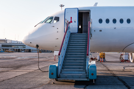 Passenger aircraft with boarding stairs at the airport apron and connected to an external power supplyの写真素材