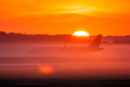 Taxiing a passenger airplane in the fog and sunriseの写真素材