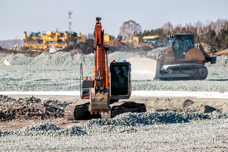 Orange excavator and yellow bulldozer dredges rubble at road constructionの写真素材