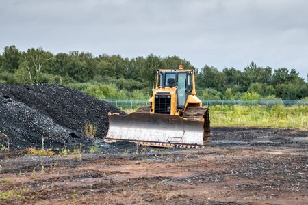 Bulldozer dredges rubble on road construction
