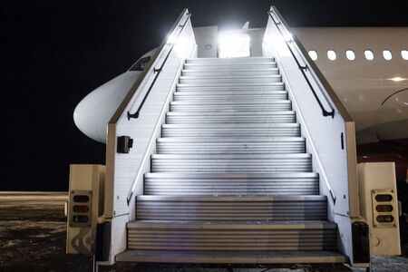 Passenger aircraft with a boarding ramp on the night airport apronの写真素材
