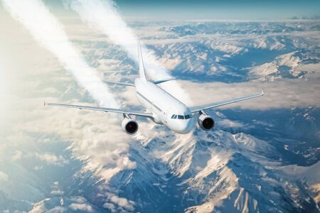 A white passenger airplane flies above the clouds above the highlands