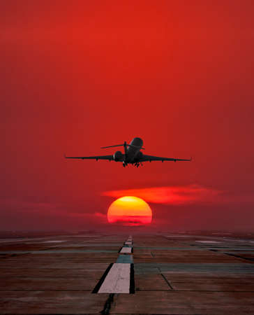 Corporate business jet take off from airport runway against the backdrop crimson sunrise