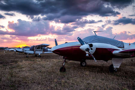 Small private aircrafts parked at the airfield at picturesque sunset