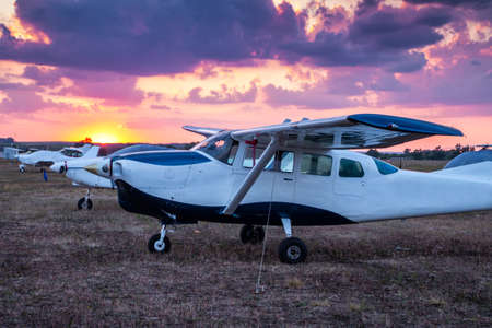 Small private airplanes parked at the airfield at scenic sunset