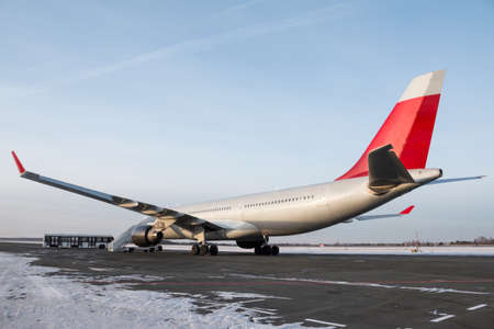 Wide body passenger airplane with boarding stairs at the winter airport apron. Shuttle bus near the aircraftの写真素材