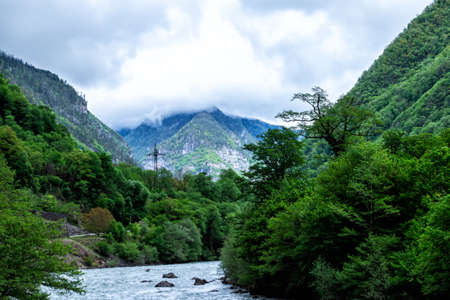 Mountain river and forest covered with low overcast cloudsの写真素材