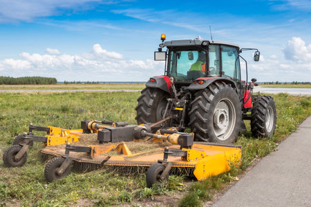 Wheel tractor with lawn mower by the roadの写真素材