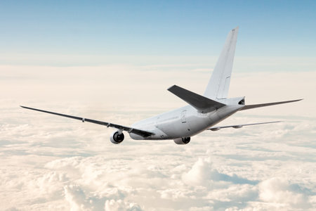 White wide body passenger aircraft flies in the air above the cloudsの写真素材