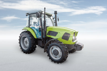 Modern wheeled tractor isolated on bright background with skyの写真素材