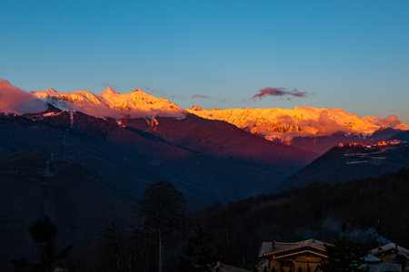 The last rays of sunlight cover the mountain peaks covered with snow. picturesque evening in the mountainsの写真素材