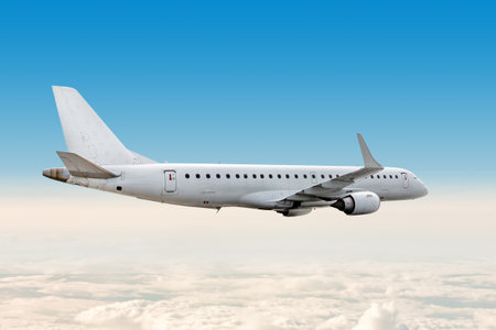 White passenger airliner flying in the air above the cloudsの写真素材