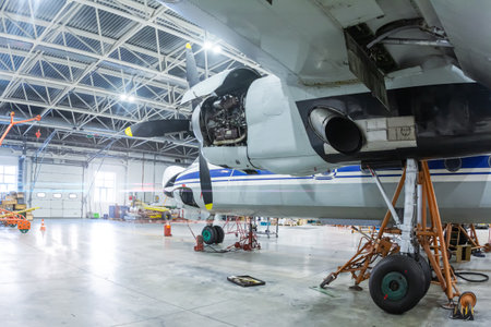 Transport turboprop airplane in the hangar. Aircraft under maintenance. Checking mechanical systems for flight operationsの写真素材