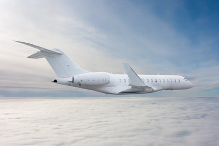 White modern luxury executive business jet flies in the air above the cloudsの写真素材