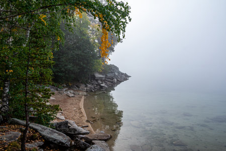 Fog on the rocky shore of a picturesque lake in autumnの写真素材