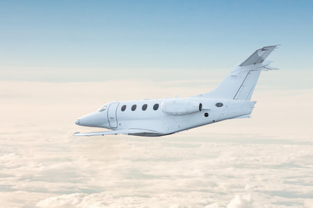White private jet fly in the air above the cloudsの写真素材