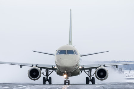 Front view of the passenger jetliner taxiing on taxiway in snowy winter dayの写真素材