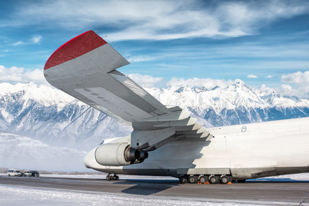 White wide body transport cargo aircraft at winter airport on the background of high picturesque...