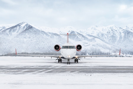 Front view of a passenger regional jet taxiing at winter airport on the background of high scenic...