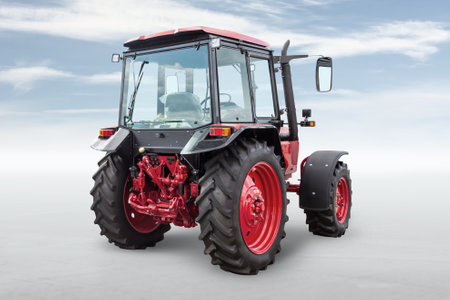 Red modern wheeled tractor isolated on bright background with skyの写真素材