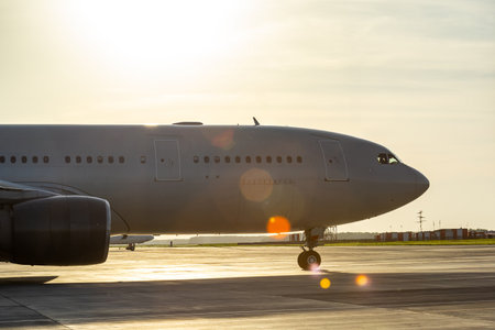 Close-up of wide body aircraft taxiing at airport in evening sunlight