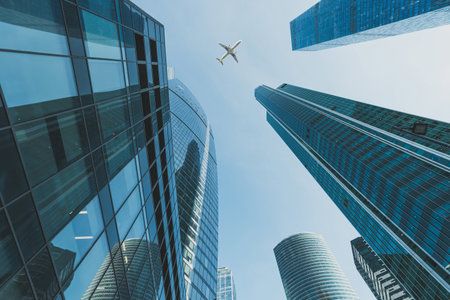 Modern glass skyscrapers and passenger airliner flying over them
