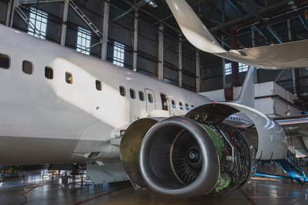 White passenger jetliner in the aircraft hangar. Airplane under maintenance. Checking mechanical...