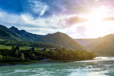 A turquoise river and scenic forested mountains. Houses on the riverbank