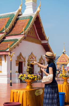 SAKON NAKHON,THAILAND-APRIL 15,2015: Young woman with her descendant are pouring water onto Buddha image at Wat Pratat Choeng Chum in songkran festival.のeditorial素材