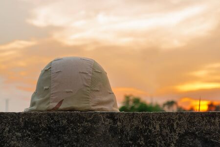 A military helmet of desert camouflage with gray sunset backgroundの写真素材