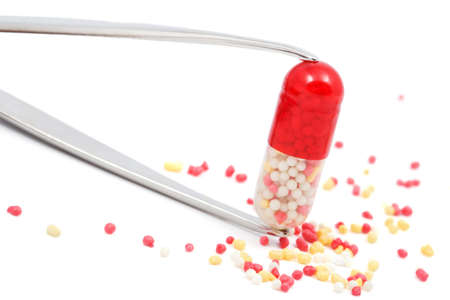 red capsule pill in a tweezers isolatedの写真素材