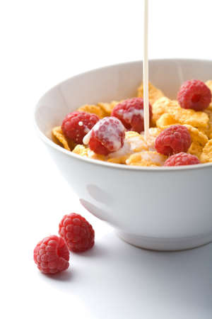 milk pouring onto muesli with raspberry isolatedの写真素材