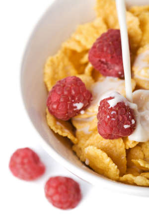 milk pouring into bowl with muesli and raspberry isolatedの写真素材