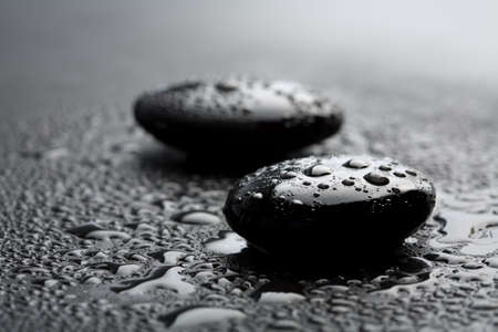 black shiny zen stones with water drops over black backgroundの写真素材