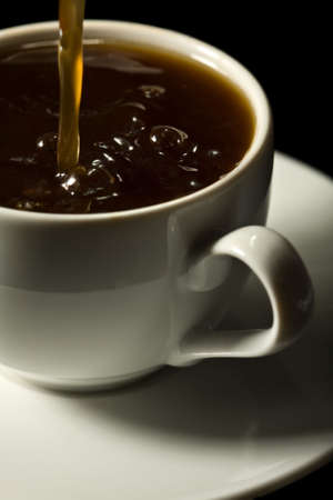 coffee splashing into white cup isolatedの写真素材