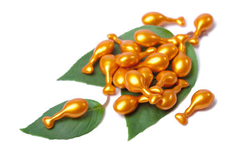 cosmetic capsules over leaves isolatedの写真素材