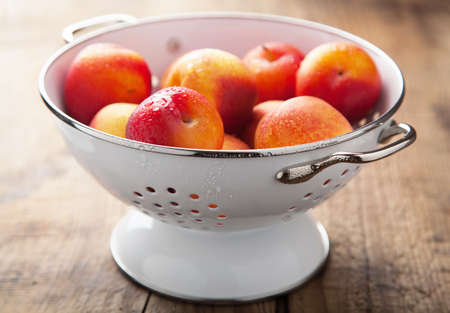 fresh nectarines and plums in colander 