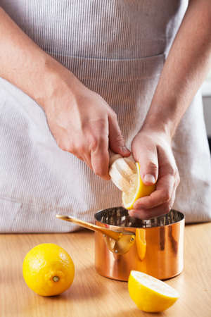 man squeezing lemon into a copper potの写真素材