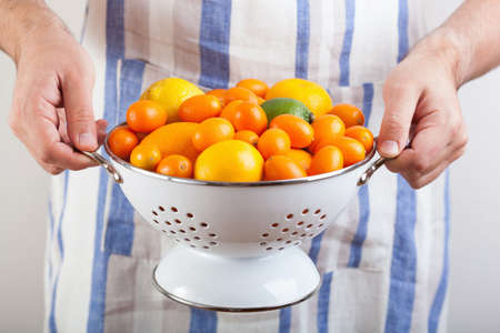 man hands holding colander with citrus fruits の写真素材